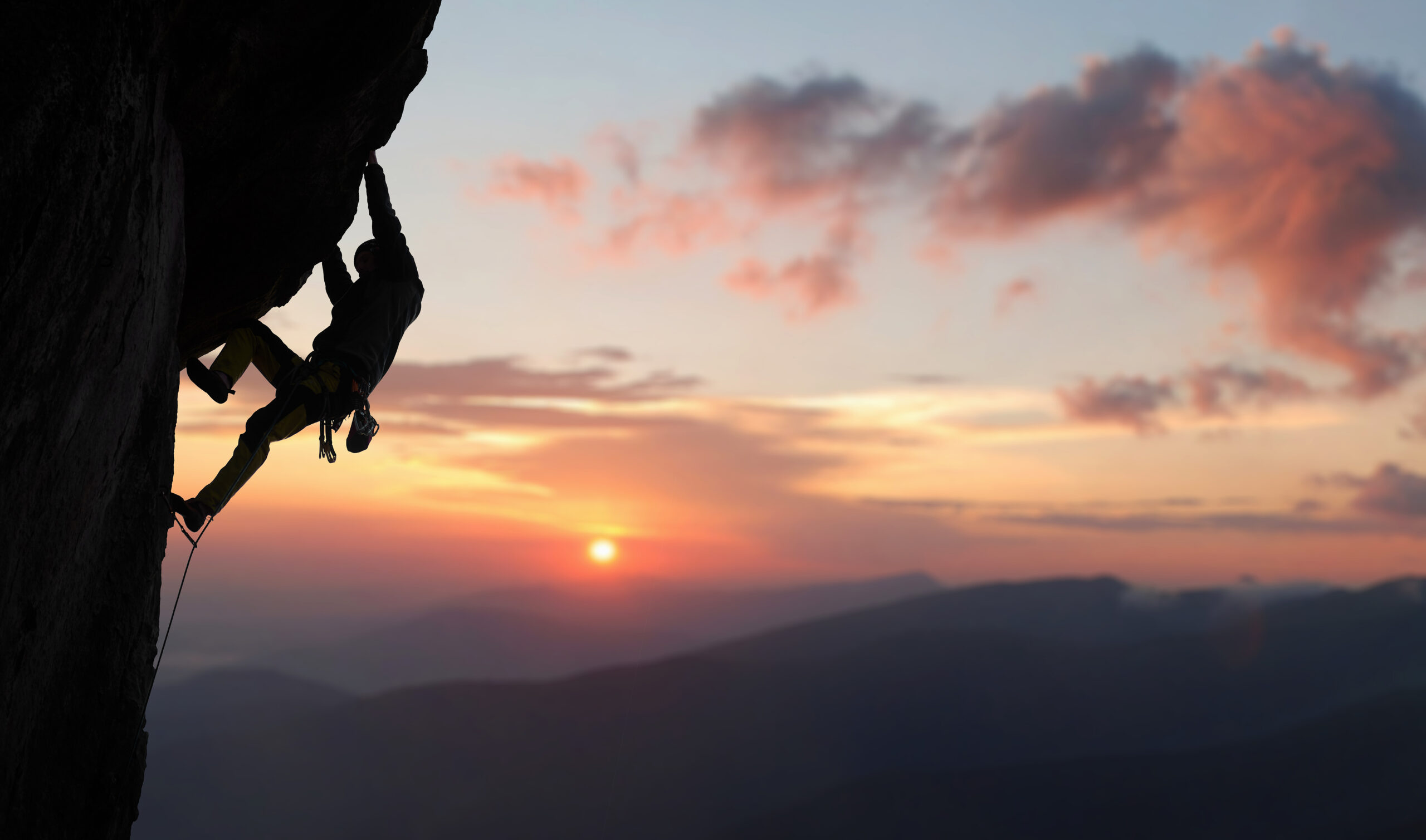 Rock climber silhouette with a sunset in the background.